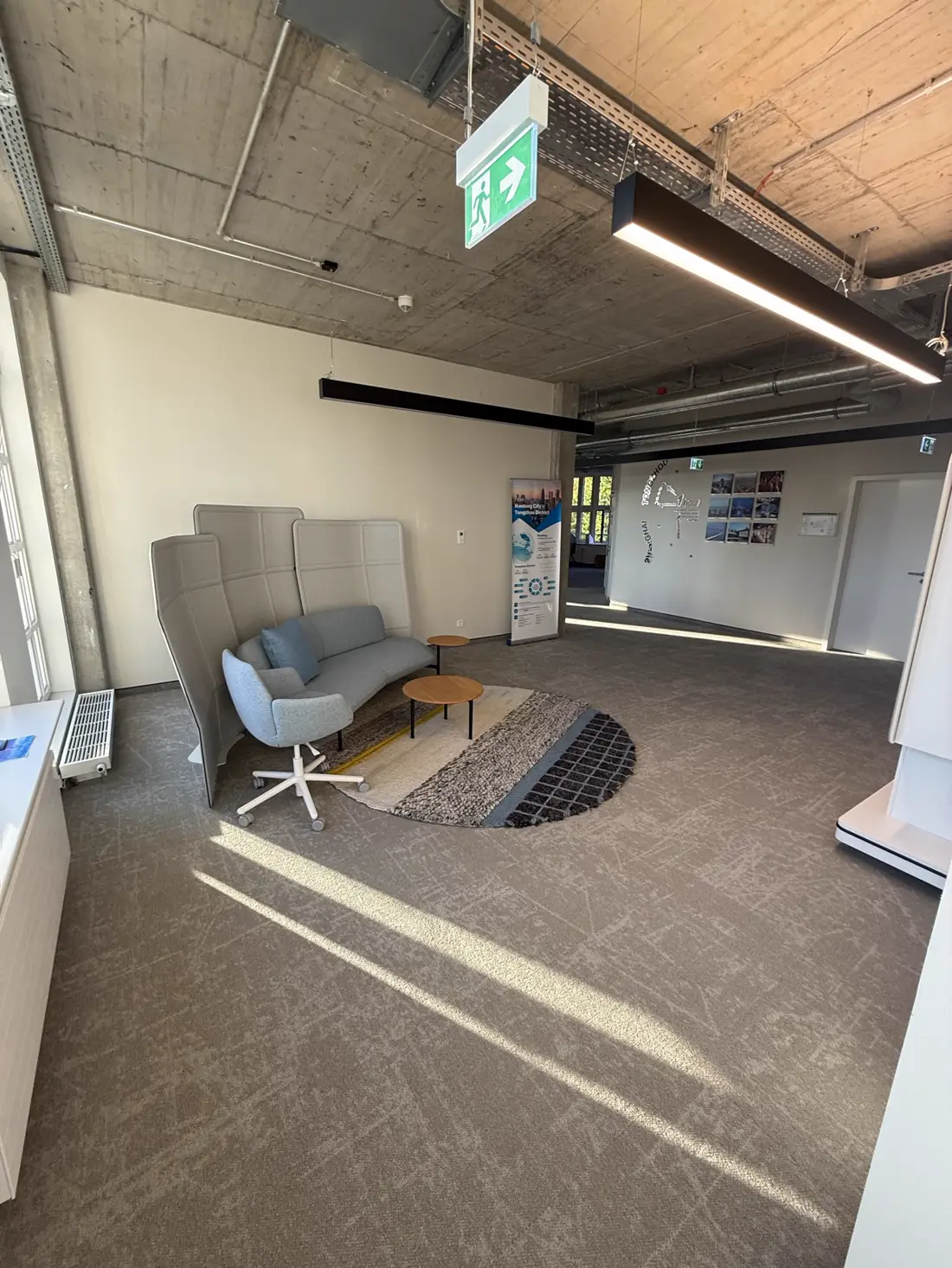 Lounge-Ecke mit Sofa, Sessel und rundem Teppich im Sonnenlicht